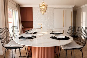A dining area with a round marble table, black wire chairs, and a gold pendant light. - Refined Apartment in Seville s Historic Centre General Casta os (Seville)