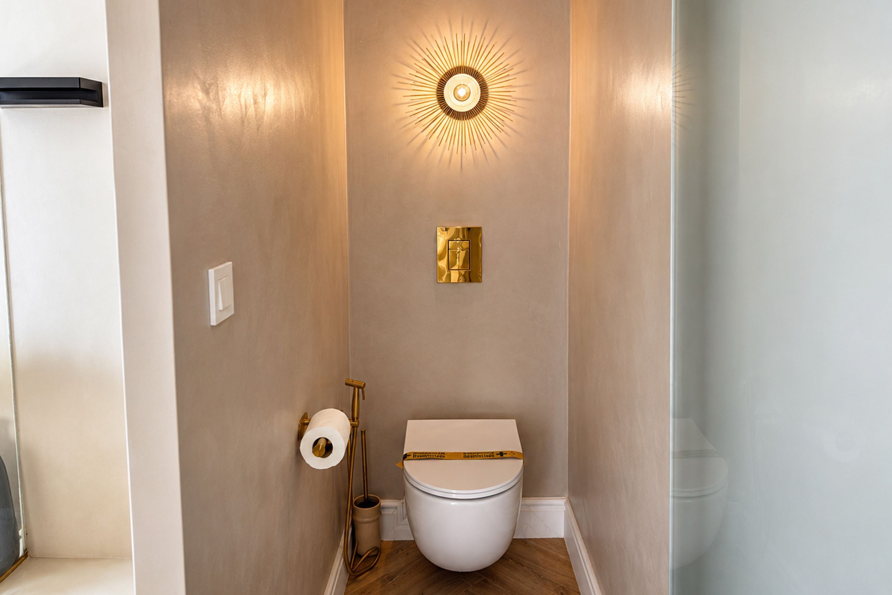 Un bagno con un water, un portasciugamani per carta igienica a parete e un punto luce fissato alla parete.