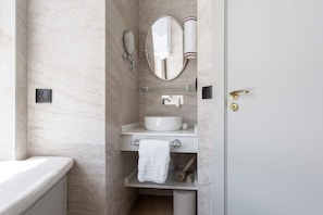 Une salle de bain avec une baignoire, un lavabo avec un miroir, une serviette et des toilettes.