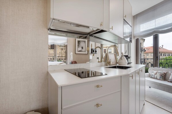 Una cocina moderna con estufa integrada, un lavamanos y una ventana con vistas a la ciudad.