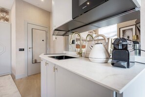Una cocina moderna con encimera blanca, electrodomésticos de acero inoxidable y un lavaplatos integrado.