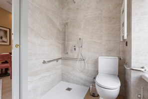 Et moderne badeværelse med bruser, toilet og gelænder.
