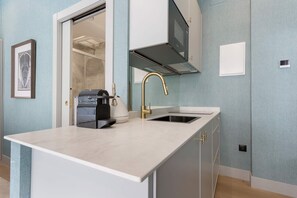 A modern kitchen with a white countertop, a gold faucet, and a built-in microwave. - Charming Studio in Salamanca Isla de la Rua II (Salamanca)