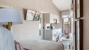 Habitación de hotel moderna con cama, escritorio, silla, televisor y vistas al exterior.