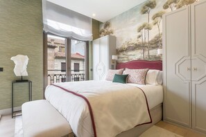 Un dormitorio con una cama grande, una mesita de noche, una lámpara, un armario y un mural en la pared.