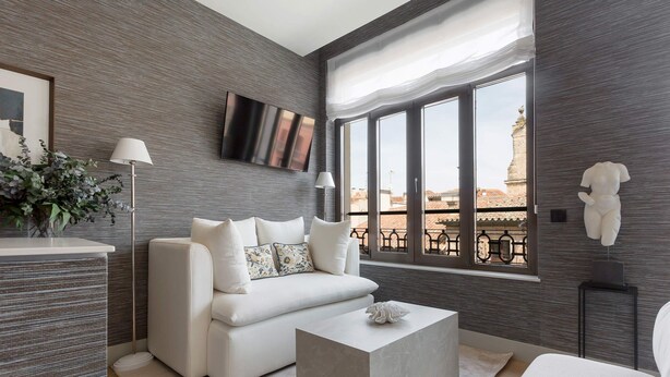 Una sala de estar moderna con un sofá blanco, una mesa de centro y un ventanal con vistas.