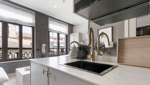 Una cocina moderna con un amplio ventanal, un lavamanos empotrado y una cafetera.
