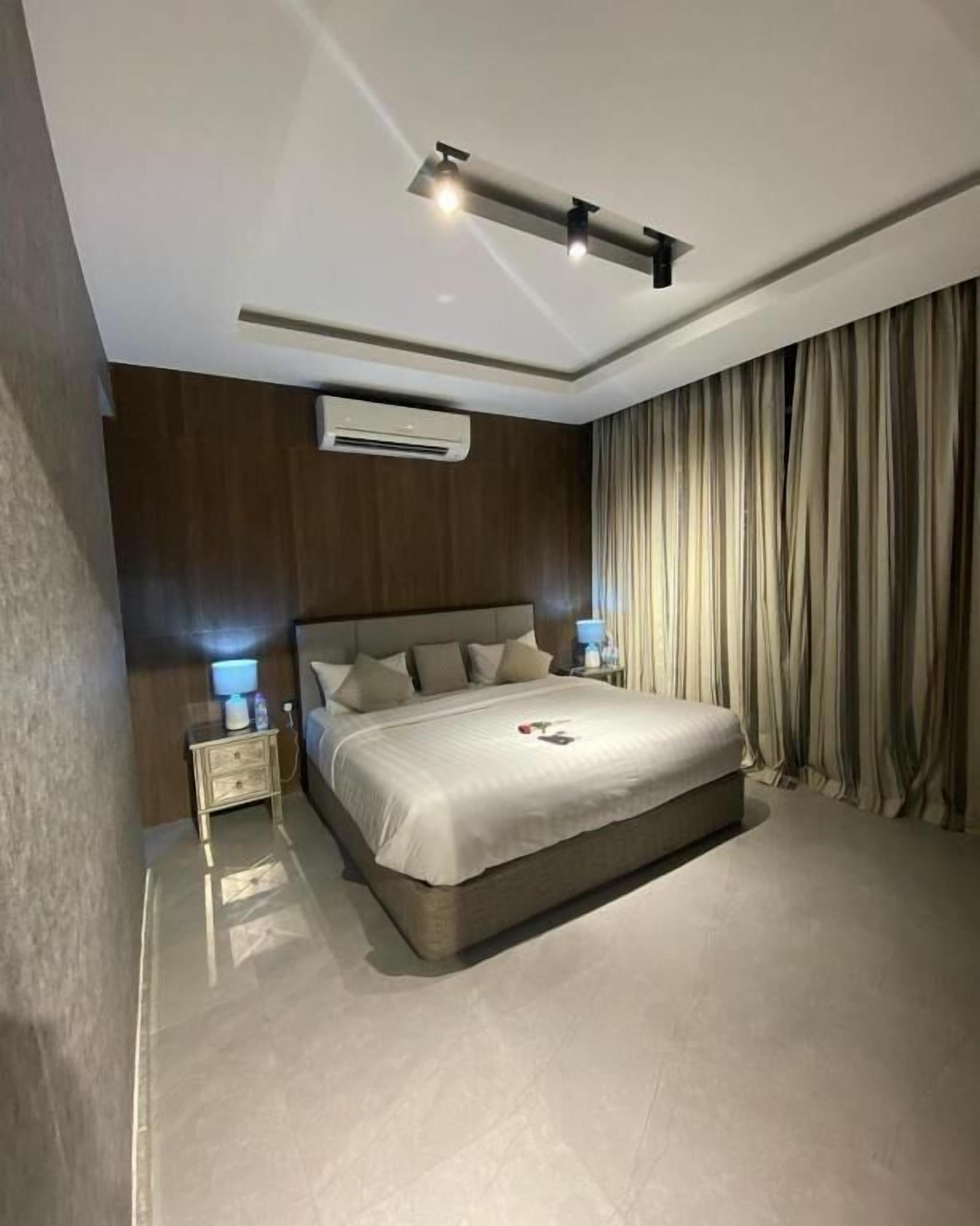 Une chambre moderne avec un grand lit, des lampes de chevet, un appareil de climatisation et un luminaire au plafond.
