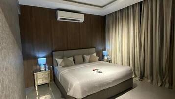 Une chambre moderne avec un grand lit, des lampes de chevet, un appareil de climatisation et un luminaire au plafond.
