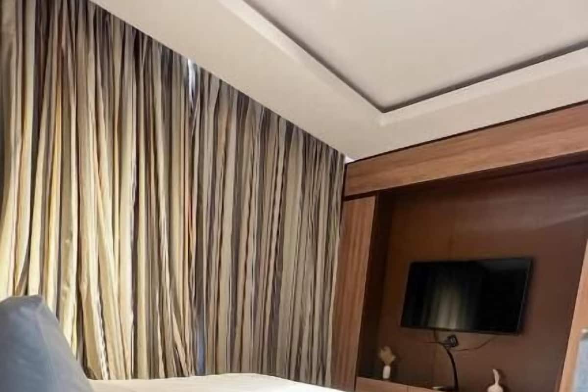 Una habitación de hotel con cama, televisión y cortina.
