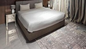 A modern bedroom with a large bed, bedside tables, an air conditioning unit, and a patterned rug. - Desert Inn Resort and Camp (Ras Al Khaimah)