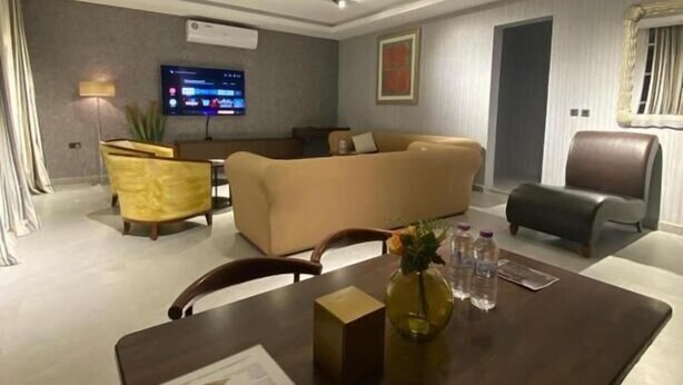 A modern living room with a sofa, a dining table with a menu, and a television. - Desert Inn Resort and Camp (Ras Al Khaimah)