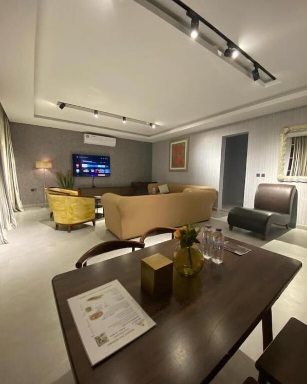 A modern living room with a sofa, a dining table with a menu, and a television.