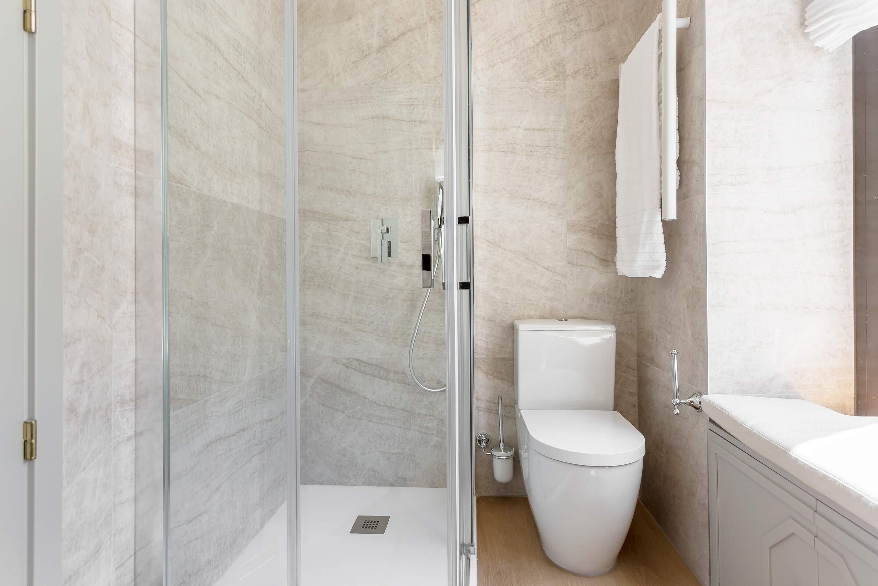 Un baño moderno con cabina de ducha de vidrio, inodoro y bañera.