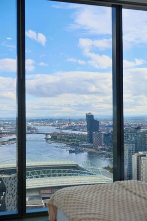 A view through a window of a cityscape with a river, a bridge, and a stadium. - Elevated Bauhaus 2BR with Bay Views (Melbourne)