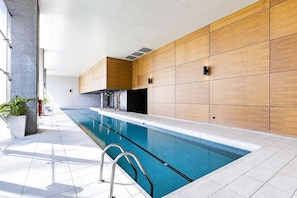 A modern indoor swimming pool with a clear view of the pool, tiled walls, and a metal ladder. - Elevated Bauhaus 2BR with Bay Views (Melbourne)