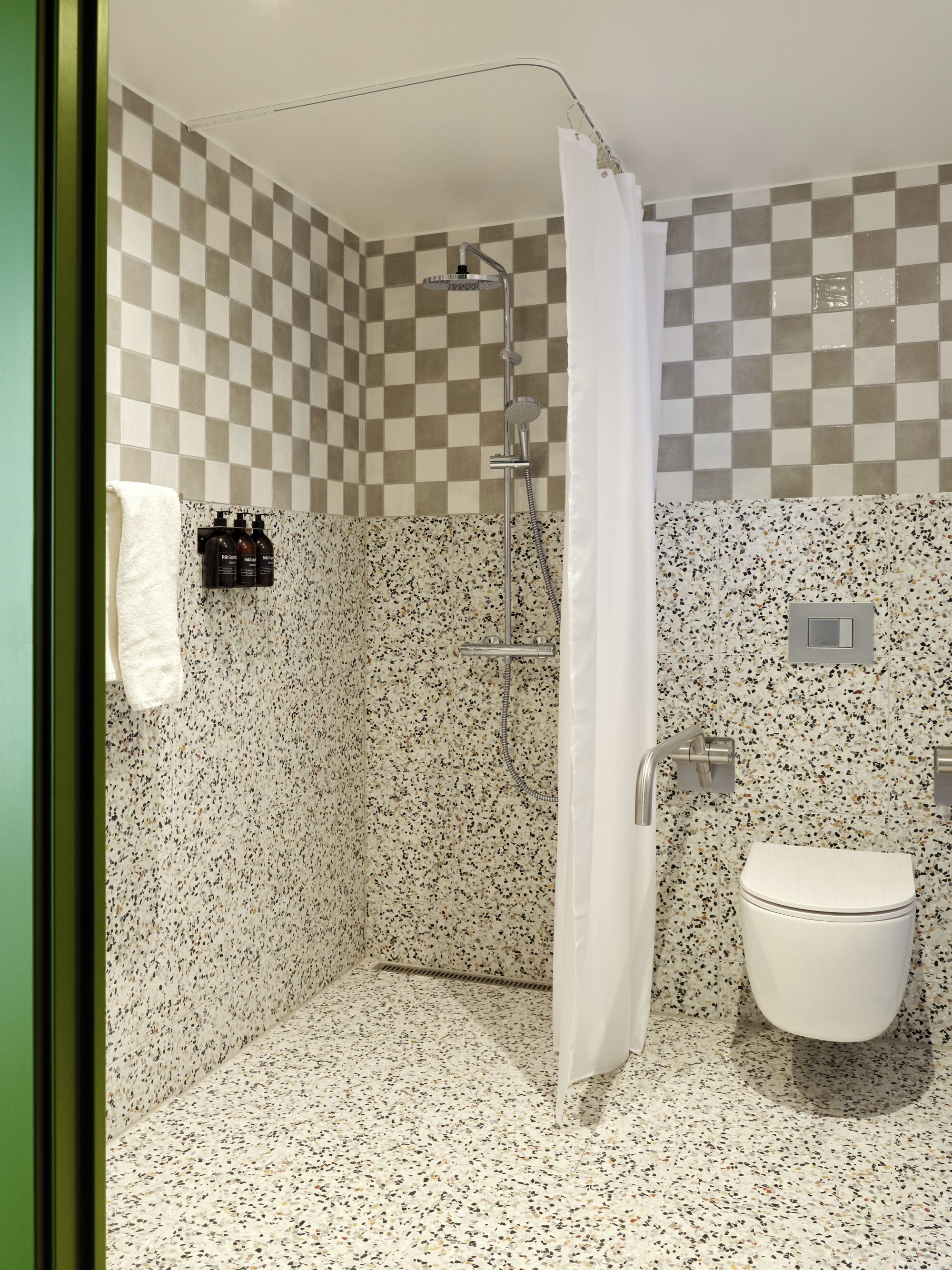 A bathroom with a shower, a toilet, and a checkered wall pattern.