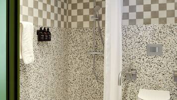 A bathroom with a shower, a toilet, and a checkered wall pattern.