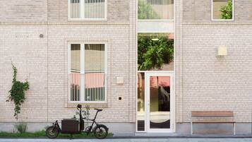 A building with a brick facade, a bicycle parked outside, and a bench on the sidewalk.