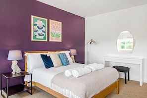 Un dormitorio con cama, mesitas de noche, escritorio y ventana.