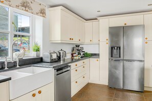 A kitchen with white cabinets, stainless steel appliances, a toaster, a coffee maker, and a water dispenser.