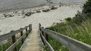 Eine Holztreppe führt zu einem Strand mit Blick auf das Meer.