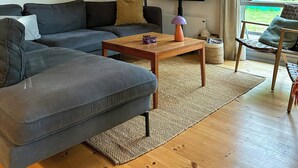 Ein modernes Wohnzimmer mit einer Eckcouch, einem Couchtisch, einem Flachbildfernseher und Kunstwerken an den Wänden.