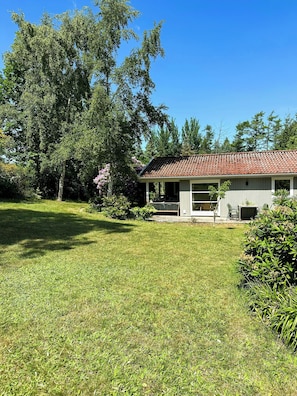 Una casa amb teulada, porxo cobert i un jardí daurat.