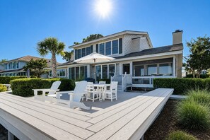 Une maison moderne dotée d’une terrasse, de mobilier d’extérieur et surplombant un ciel bleu dégagé.