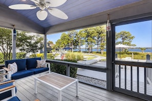 Eine überdachte Terrasse im Freien mit einem blauen Sofa, einem kleinen Tisch und einem Deckenventilator.