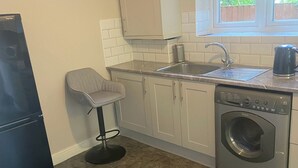 A compact kitchen with a built-in washing machine, a sink, and a refrigerator. - London Charm - 3 Bedroom House (London)