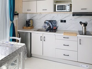 Cocina compacta con microondas, cafetera y lavabo.