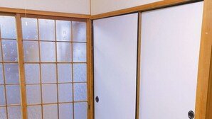 Een kamer met tatami vloerbedekking, verschuifbare shoji deuren en een houten plafond.