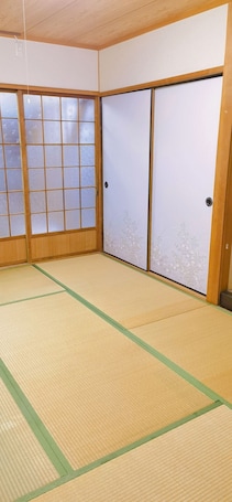 A room with tatami flooring, sliding shoji doors, and a wooden ceiling.. Start your dreamy Japan trip at the Kobayashi Guest House, Osaka!