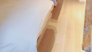 Een kamer met twee bedden, houten balken, een lamp, een deur en een houten vloer.