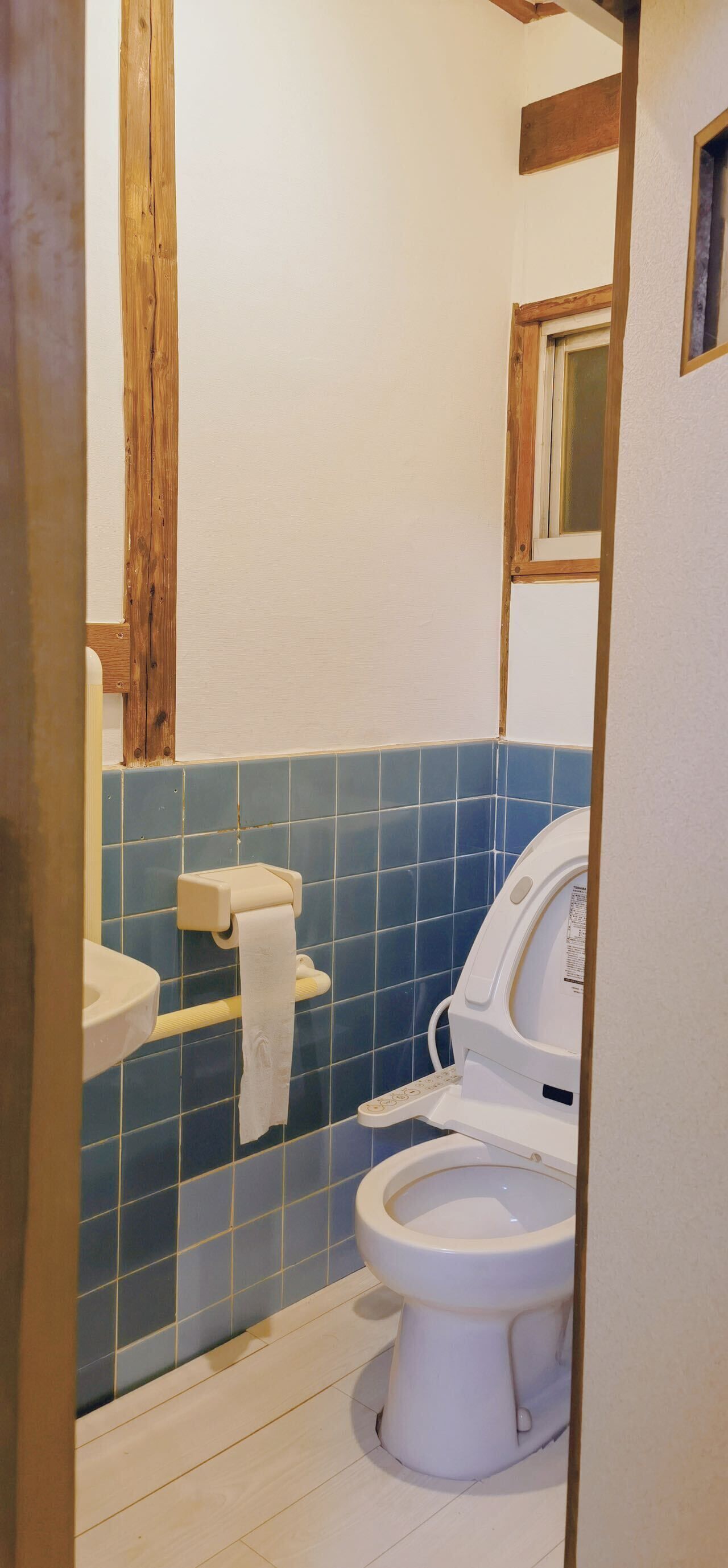 A bathroom with a toilet, a sink, and a towel dispenser.