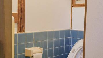 A bathroom with a toilet, a sink, and a towel dispenser.