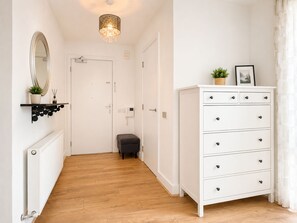 A hallway with a white door, a radiator, a grey bench, a white dresser with drawers, and a hanging mirror. - Free Underground Parking l 5 mins Wembley Stadium/Arena/Park Station (Wembley)