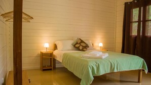 Une chambre avec un lit, deux tables de chevet, un luminaire suspendu et une fenêtre avec des rideaux.