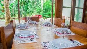 Une table à manger dressée avec des assiettes, des verres et des couverts, entourée de chaises en bois.