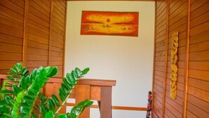 Un intérieur en bois orné d’un tableau représentant un coucher de soleil, une table en bois et une plante.