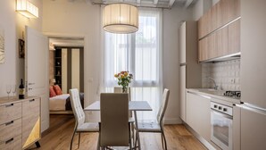 A modern kitchen with wooden cabinets, a dining area with a table and chairs, and a large window with curtains. - Albero Apartment by Maison Florence (Florence)