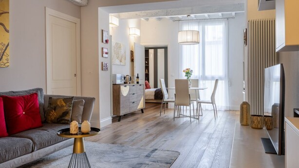 A modern living room with a grey sofa, a coffee table, and a dining area with a white table and chairs. - Albero Apartment by Maison Florence (Florence)