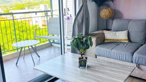 Ein Balkon mit Tisch, einer Couch und einem Blumentopf.