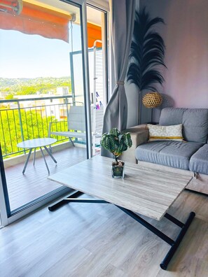 Ein Balkon mit Tisch, einer Couch und einem Blumentopf.