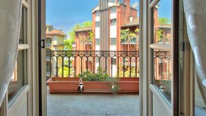 Een open balkon met uitzicht op omliggende gebouwen, een metalen hek en plantenbakken.
