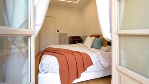 Een slaapkamer met een bed, een radiator, een nachtkastje en een raam met gordijnen.
