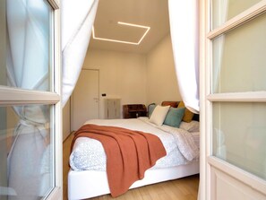 Ein Schlafzimmer mit Bett, Heizkörper, Nachttisch und einem Fenster mit Vorhängen.