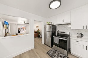 Eine moderne Küche mit weißen Schränken, Edelstahlgeräten und einem schwarz-weißen Teppich.