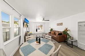 Ein modernes Wohnzimmer mit einem runden Tisch, einem braunen Sofa und einem Deckenventilator.